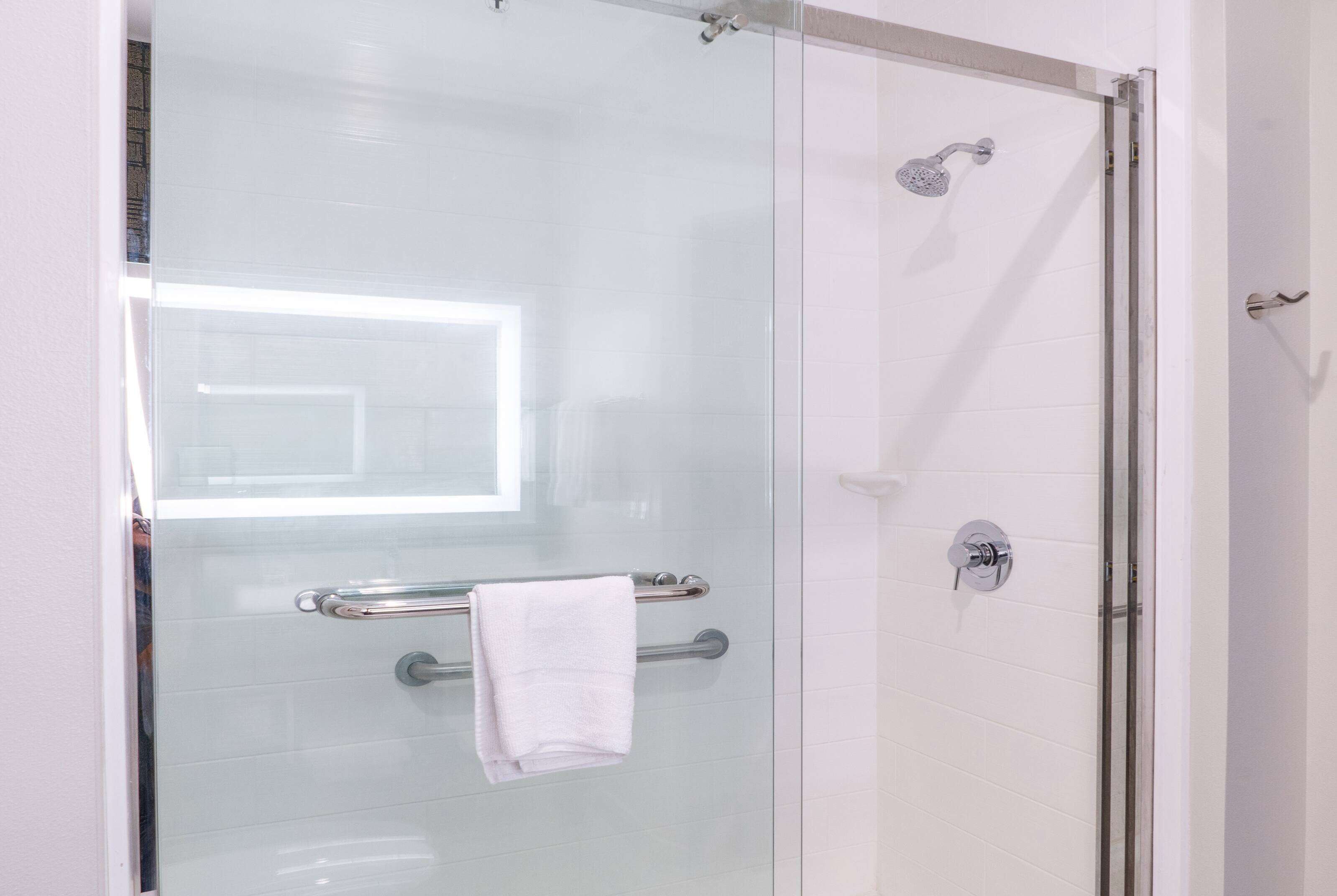 A glass-enclosed shower with a handheld showerhead, a towel rack, and a glass door.