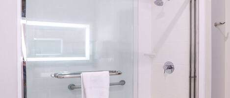 A glass-enclosed shower with a handheld showerhead, a towel rack, and a glass door.