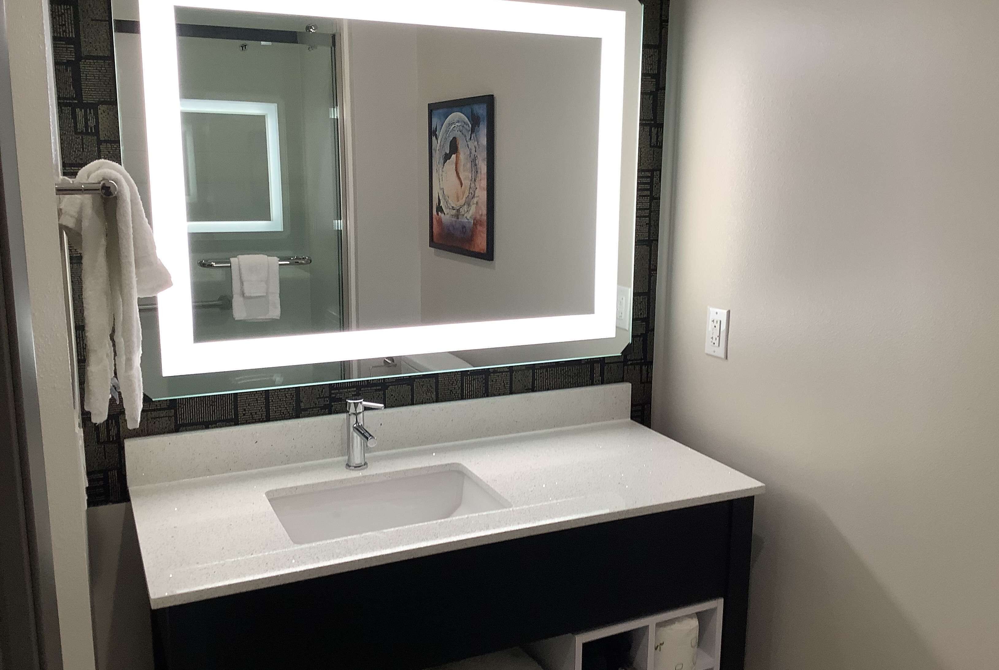 A bathroom with a large mirror, a white sink, and a towel rack.