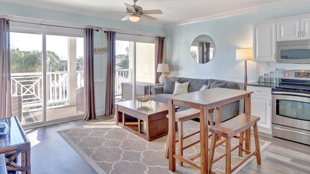 Een ruime woonkamer met een balkon, een eettafel en een keuken met moderne apparatuur.