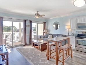 A spacious living area with a balcony, a dining table, and a kitchen with modern appliances.