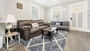 A living room with a brown leather sofa, a gray sofa, a coffee table, and a patterned rug. - Nibley Park Sugarhouse Bungalow (Salt Lake City)