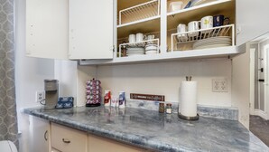 A kitchen with a marble countertop, a coffee maker, a paper towel holder, and a sign that says "Life Begins with Coffee." - Nibley Park Sugarhouse Bungalow (Salt Lake City)