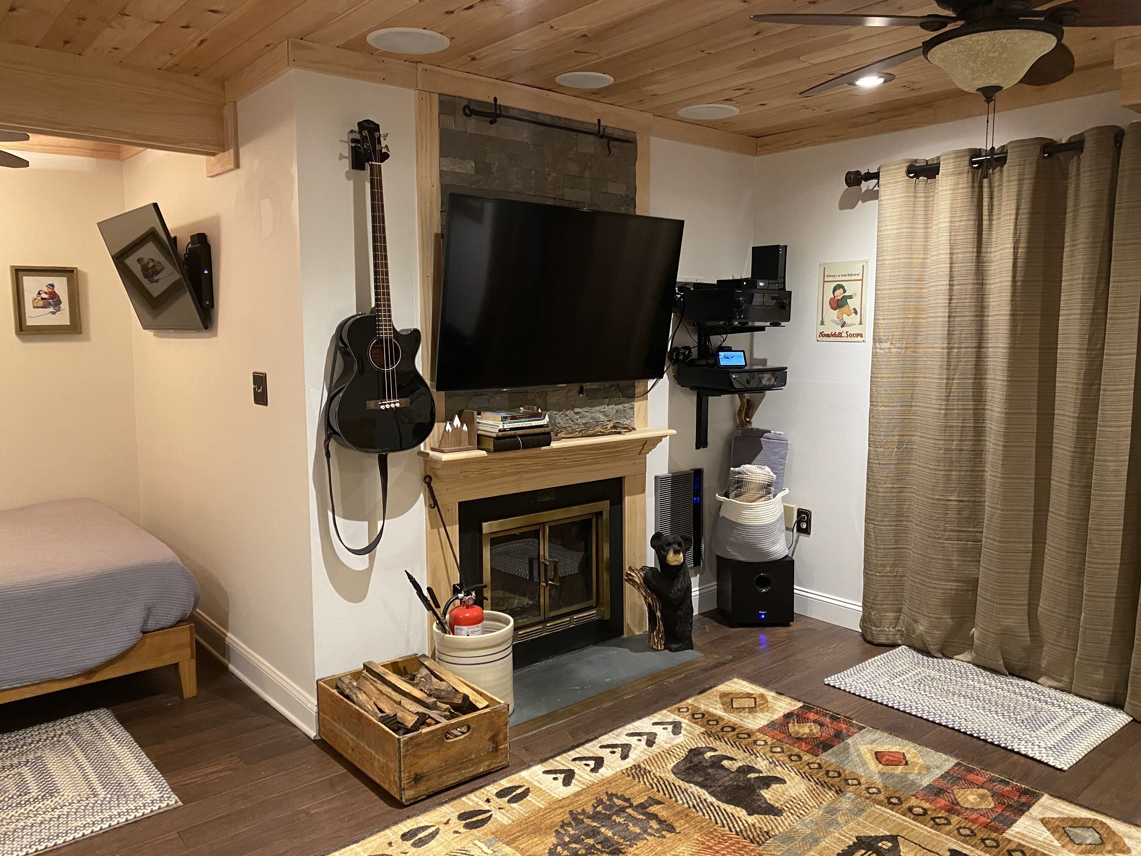 A cozy living room with a fireplace, a television, and a guitar.