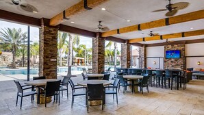 A spacious indoor area with a pool, multiple seating arrangements, and a television screen.