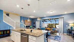 A modern kitchen with granite countertops, stainless steel appliances, and pendant lighting.