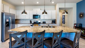 A modern kitchen with granite countertops, stainless steel appliances, and pendant lighting.