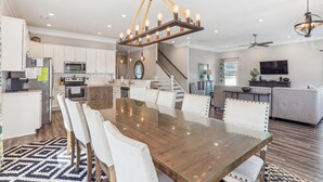 A spacious kitchen with white cabinets, a stainless steel refrigerator, and a microwave. - Shore Beats Work 6BR 5BA Beach Home with Outdoor Pool, Hot tub, and Game Room (North Myrtle Beach)