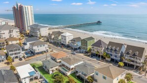 A coastal residential area with beachfront properties, a pier, and a clear view of the ocean.