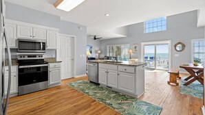 A spacious kitchen with white cabinets, a stainless steel oven, and a large island with a sink.