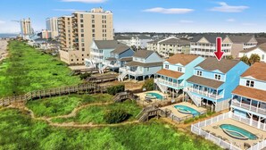 A coastal residential area with beachfront properties, a swimming pool, and a wooden boardwalk.