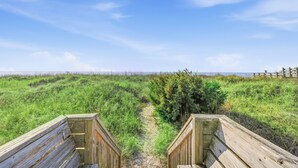 A wooden pathway leading to a beach with a clear sky.
