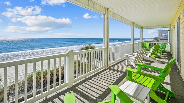 A covered deck with white railings overlooking a beach. - Casablanca - Luxury Oceanfront Home in Cherry Grove with Game Room & Pool (North Myrtle Beach)