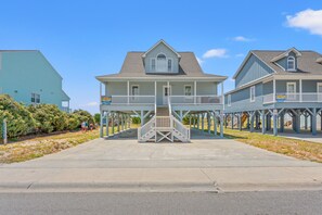 A beachfront property with a covered walkway leading to a house with a balcony.
