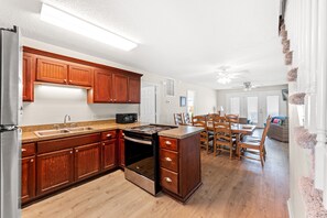 Una cocina moderna con armarios de madera, estufa integrada y un comedor con mesa y sillas.