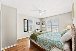 A bedroom with a bed, a ceiling fan, and two windows with blinds. - Cassie - Pet Friendly, Oceanfront home in Cherry Grove (North Myrtle Beach)