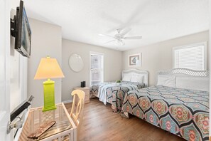 A bedroom with a bed, a desk with a lamp, a chair, a ceiling fan, and a window with blinds. - Cassie - Pet Friendly, Oceanfront home in Cherry Grove (North Myrtle Beach)
