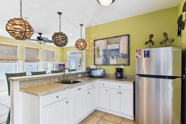 A kitchen with white cabinets, a stainless steel refrigerator, a microwave, and a coffee maker.