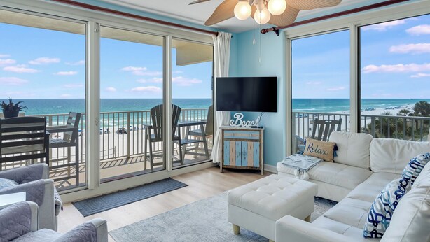 Un salon spacieux doté d’une grande porte-fenêtre coulissante donnant sur un balcon avec vue sur la plage.