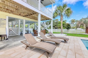 Relax by the pool in a serene outdoor space surrounded by lush greenery and comfortable lounge chairs.