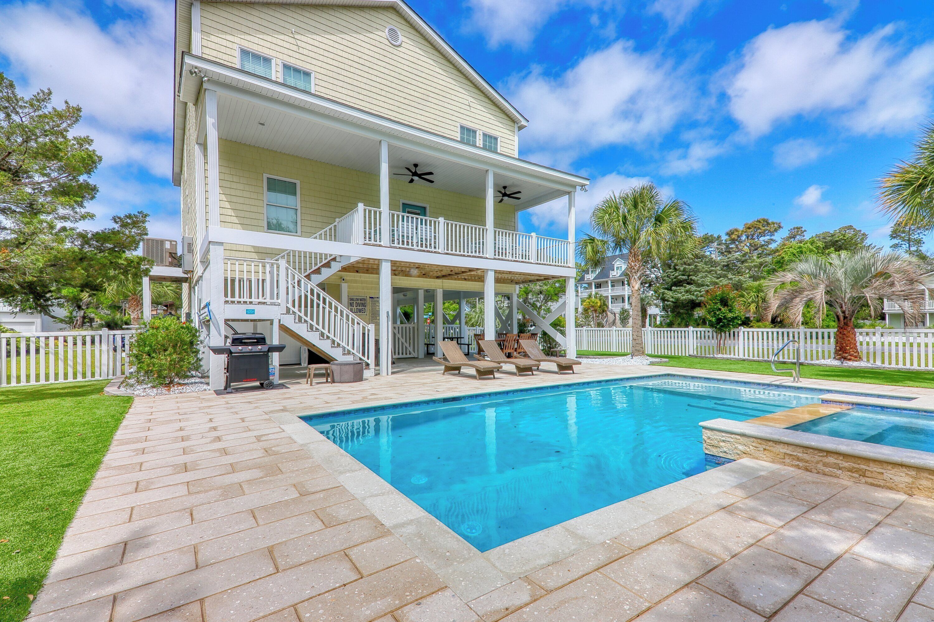 A two-story house with a covered patio and a swimming pool.