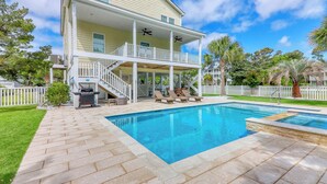 Ein zweigeschossiges Haus mit einer überdachten Terrasse und einem Swimmingpool.