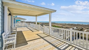A wooden deck with white railings overlooking a beach. - Chase - Pet Friendly Oceanfront House in Cherry Grove (North Myrtle Beach)