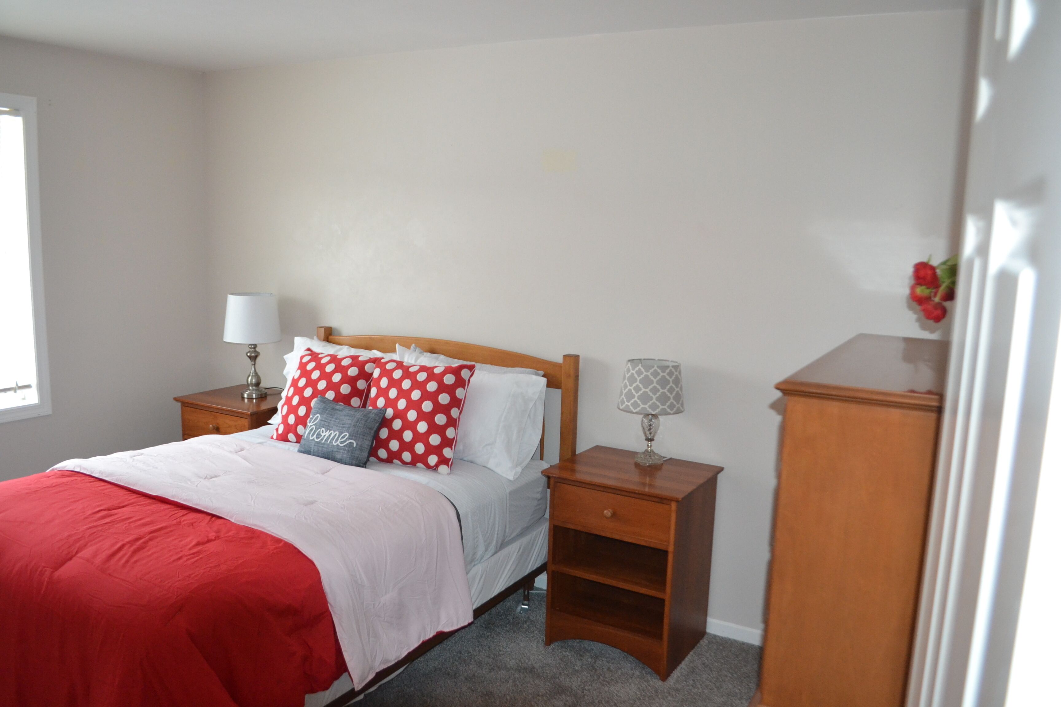 A bedroom with a bed, two nightstands, a lamp, and a wooden cabinet.