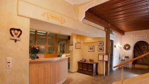 A reception area with a wooden reception desk, a glass window, and a wall-mounted sign that reads "Reception". - Tauernkoenig (Tweng)