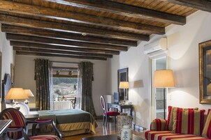Una habitación acogedora con techo de madera, una cama, un escritorio con ordenador, una silla y un sofá.