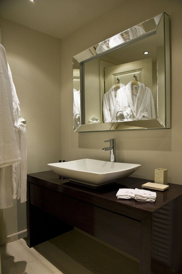 A modern bathroom with a large mirror, a white sink, dark wooden vanity, and a towel rack. - Archontiko Kaltezioti (Tripoli)