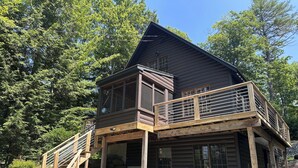 A two-story log cabin with a balcony and a wooden staircase leading to the upper level.