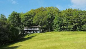 A two-story house with a balcony, surrounded by lush green trees and grass. - Eagle Landing, Views, WI-FI, Private, Spacious! (Boone)