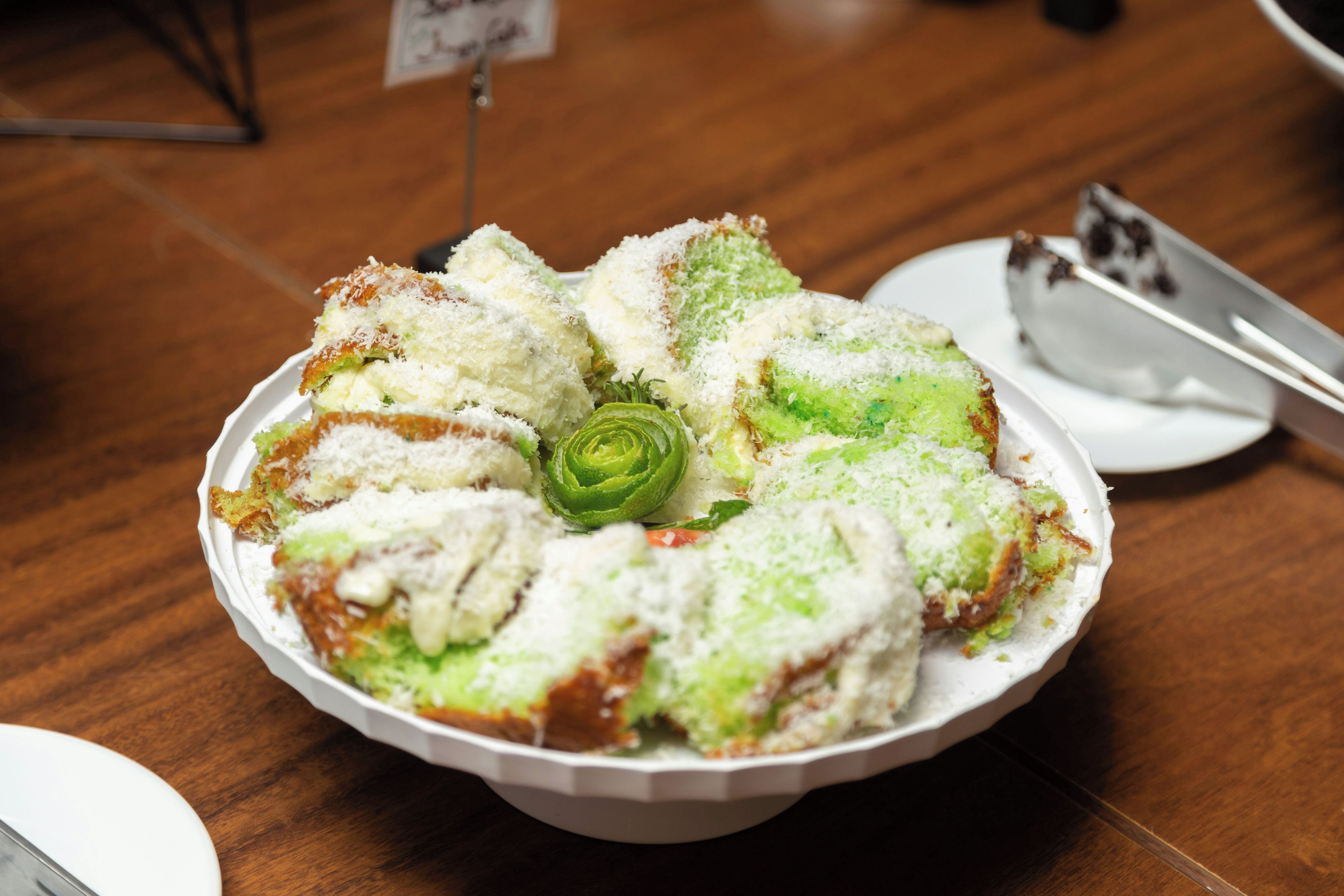 A round white plate with a food item, possibly a cake, on a wooden table.