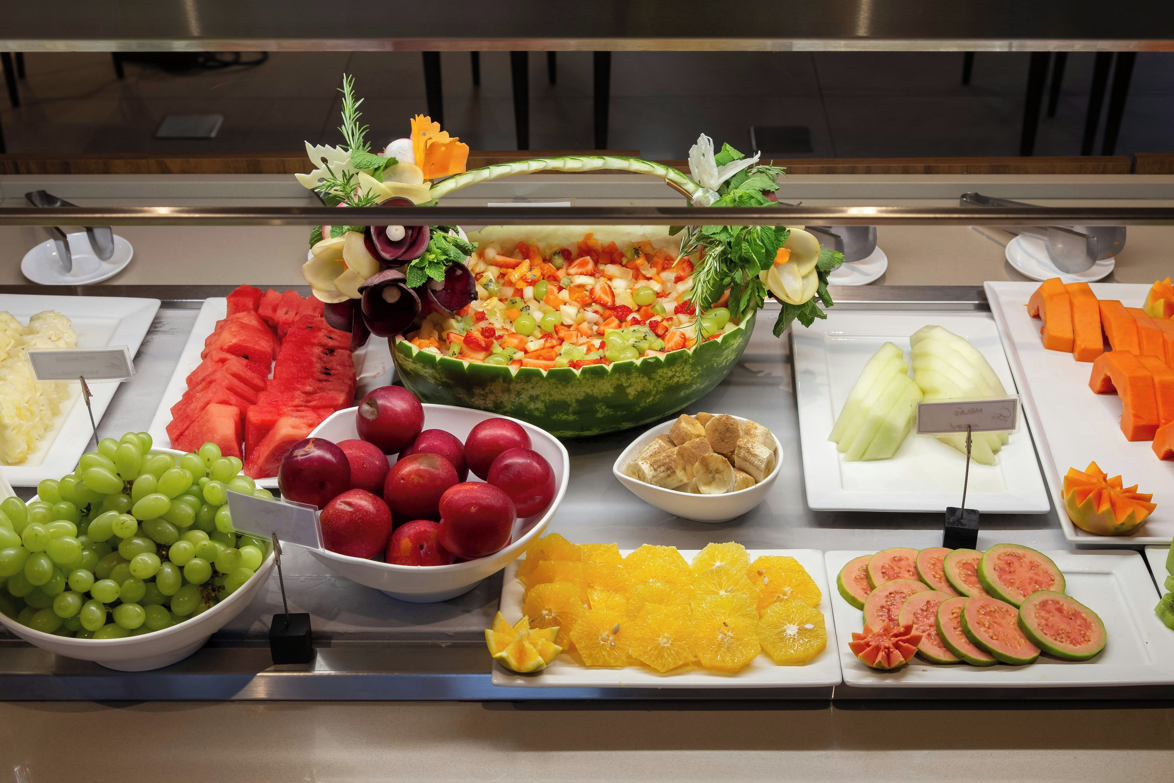 A buffet with various fruits and vegetables, including watermelon, grapes, and sliced oranges.