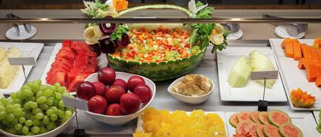 A buffet with various fruits and vegetables, including watermelon, grapes, and sliced oranges.