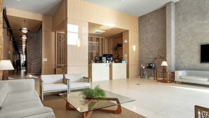 A modern hotel lobby with a reception desk, seating area, and a staircase leading to other floors. - Hilton Garden Inn Itajai (Itajai)