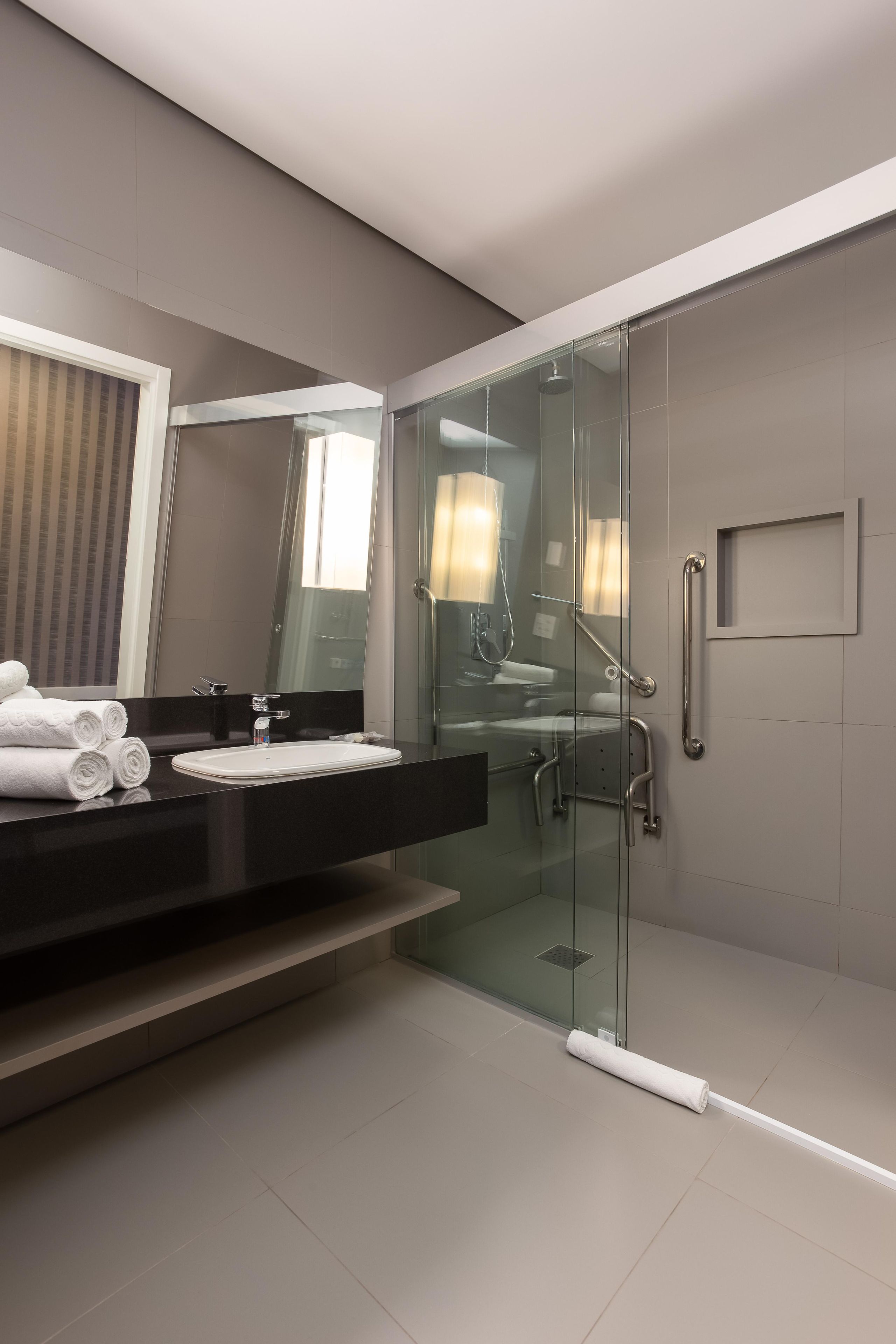 A modern bathroom with a glass-enclosed shower, a vanity with a sink, and a mirror.
