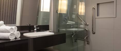 A modern bathroom with a glass-enclosed shower, a vanity with a sink, and a mirror.