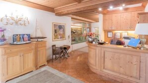 A wooden interior with a kitchen area, a dining table, and a chair. - Hotel Belvedere (Pieve di Cadore)