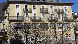 A multi-story building with balconies, a flat roof, and a clear sky. - Hotel Belvedere (Pieve di Cadore)