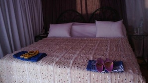 A bed with a patterned bedspread, pillows, and a pair of slippers on a blue cloth. - Tizi Plus Desert (Zagora)
