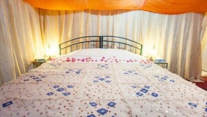 A bed with a patterned bedspread, a headboard, and curtains. - Tizi Plus Desert (Zagora)