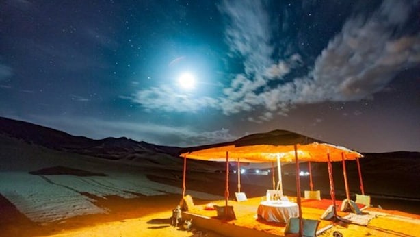 A desert camp with a large, open, covered seating area under a canopy, surrounded by sand dunes. - Tizi Plus Desert (Zagora)