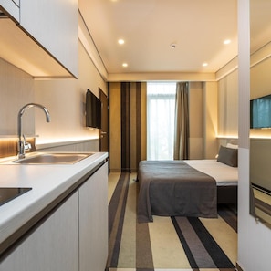 A hotel room with a bed, a sink, a flat-screen TV, and a window with curtains. - Grand Baltic Dunes (Palanga)