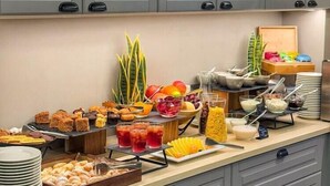 A kitchen with grey cabinets, a buffet table with various food items, and a fruit display. - Grand Baltic Dunes (Palanga)