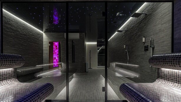 A modern, dimly lit hallway with a starry ceiling, leading to a room with a purple-lit wall. - Grand Baltic Dunes (Palanga)