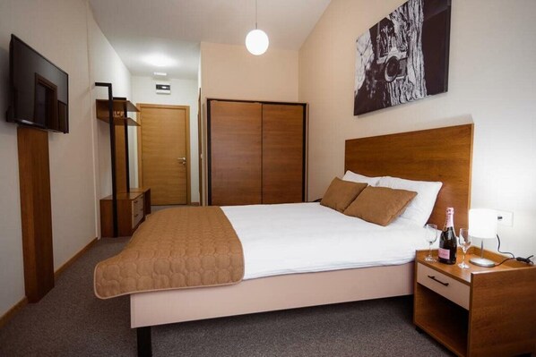 A neatly arranged bedroom with a bed, bedside table, and a TV mounted on the wall. - Sajam Hotel Leskovac (Leskovac)