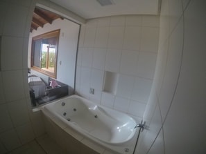 A bathroom with a large bathtub, a window, and tiled walls. - Cabana à Beira D'água Linda Vista (Imbituba)