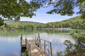 A wooden dock extending into calm water, surrounded by lush greenery and hills in the background. - Petit Crest Villas (Jasper)